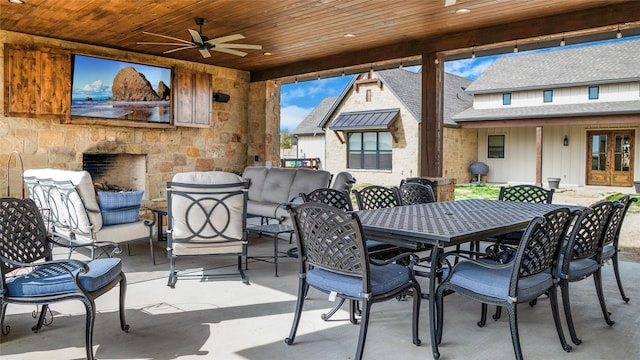 view of patio featuring an outdoor living space with a fireplace, outdoor dining space, a ceiling fan, and french doors