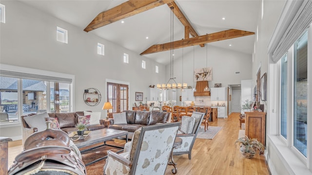 living area featuring a chandelier, high vaulted ceiling, light wood-style floors, french doors, and beamed ceiling