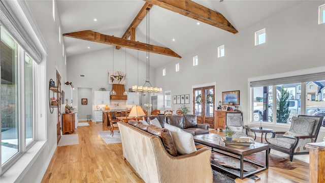 living area featuring high vaulted ceiling, light wood finished floors, beamed ceiling, and a notable chandelier