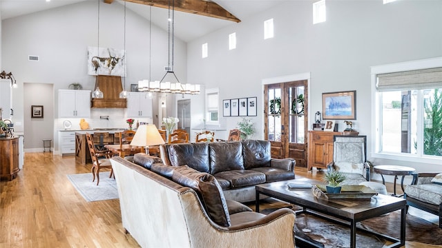 living area featuring high vaulted ceiling, a notable chandelier, visible vents, light wood finished floors, and beamed ceiling