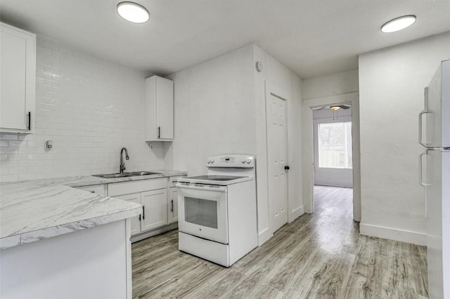 kitchen featuring light wood finished floors, backsplash, white cabinets, a sink, and white appliances