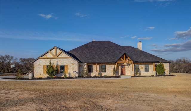 view of front of property with stone siding, roof with shingles, a chimney, and a front lawn