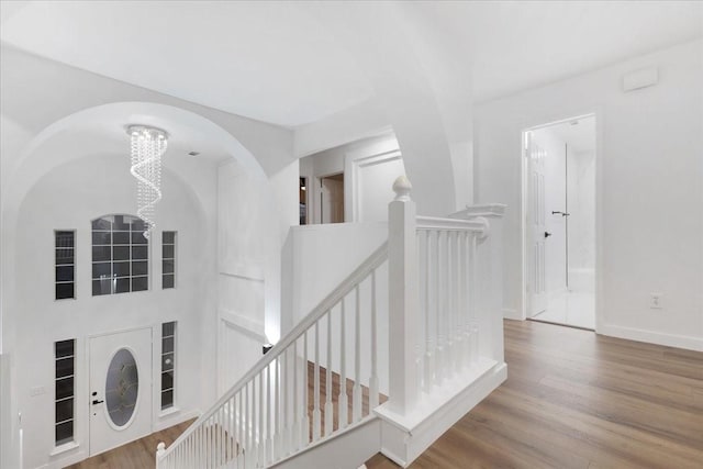 hall with a chandelier, baseboards, an upstairs landing, and wood finished floors