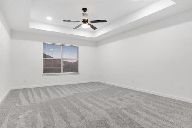 carpeted spare room featuring a ceiling fan, a tray ceiling, baseboards, and recessed lighting