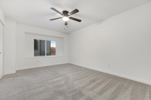 carpeted empty room featuring baseboards and a ceiling fan