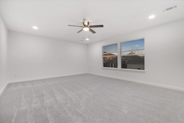 carpeted spare room featuring ceiling fan, visible vents, and baseboards