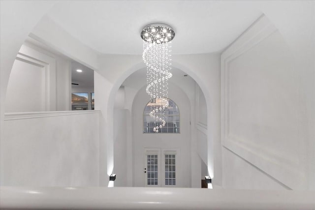 hallway featuring an inviting chandelier and french doors