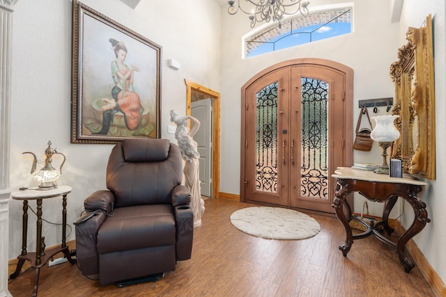 foyer entrance featuring french doors, a notable chandelier, baseboards, and wood finished floors