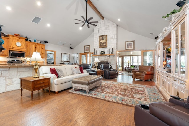 living area featuring visible vents, wood finished floors, beamed ceiling, a fireplace, and high vaulted ceiling