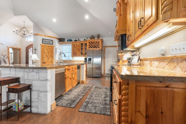 kitchen featuring wood finished floors, a sink, appliances with stainless steel finishes, a kitchen bar, and glass insert cabinets