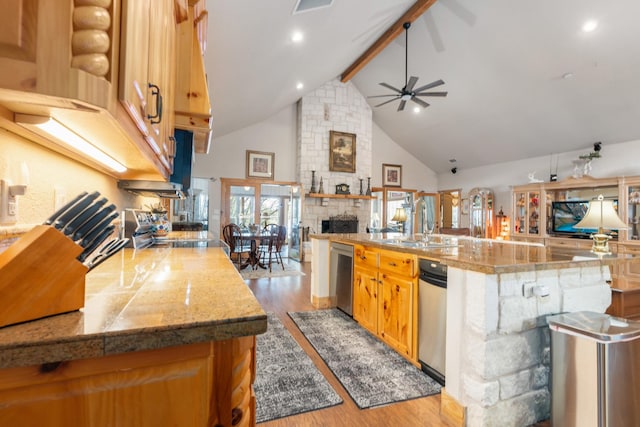 kitchen featuring open floor plan, a fireplace, a sink, and stainless steel dishwasher