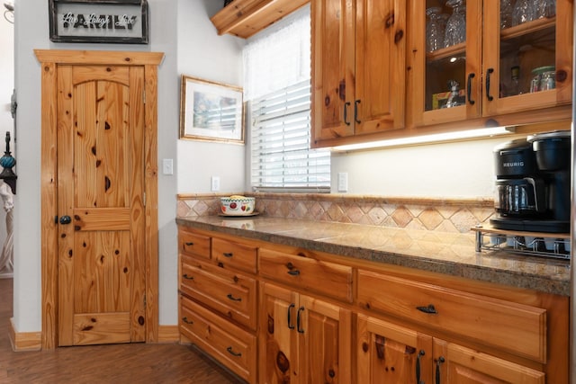 kitchen with glass insert cabinets, brown cabinets, and wood finished floors