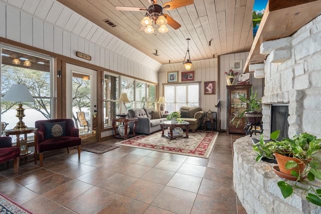 living room featuring ceiling fan, dark tile patterned floors, a fireplace, visible vents, and wood ceiling