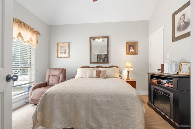 bedroom with a glass covered fireplace, light carpet, and baseboards