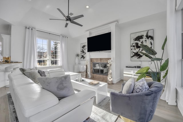 living area with light wood-style flooring, a ceiling fan, and a tile fireplace