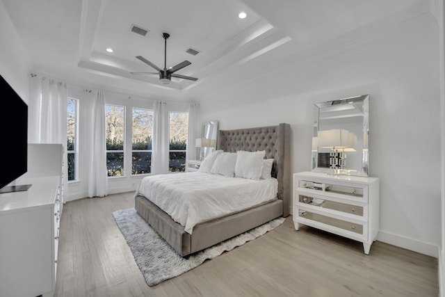 bedroom featuring light wood-type flooring, a raised ceiling, visible vents, and recessed lighting