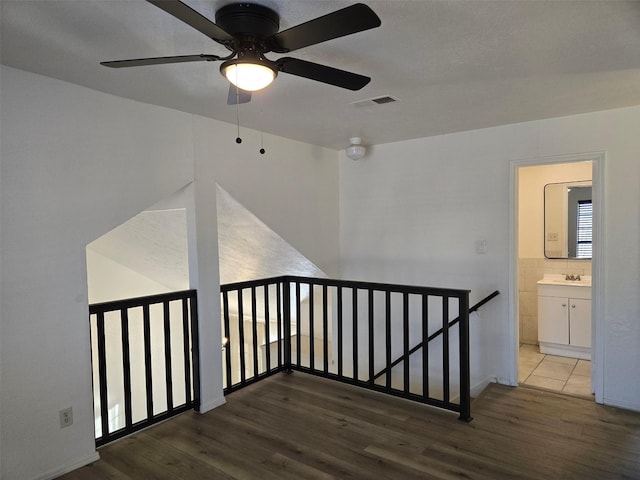 corridor featuring an upstairs landing, wood finished floors, and visible vents