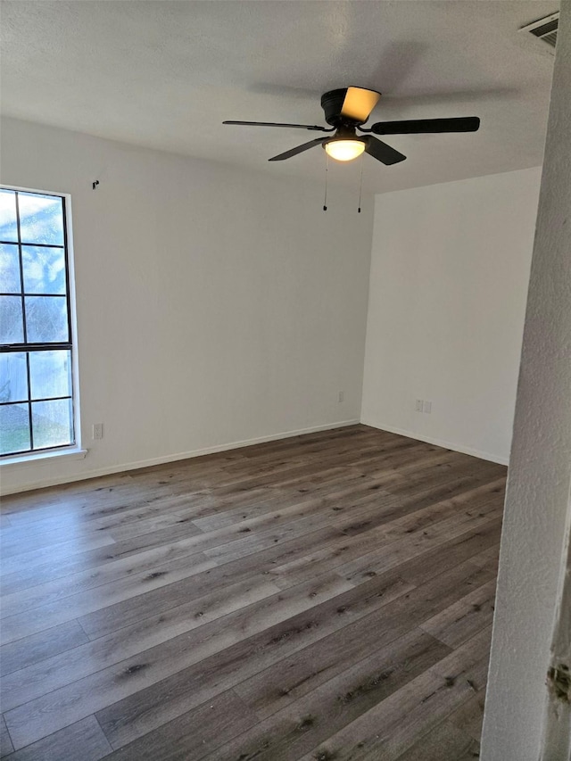 empty room featuring a textured ceiling, visible vents, and wood finished floors