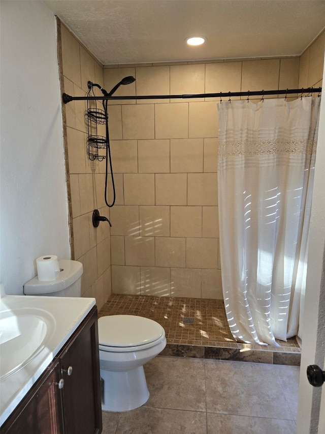 bathroom with toilet, tile patterned floors, tiled shower, and vanity