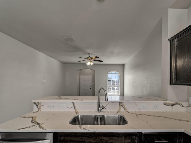 kitchen featuring ceiling fan, visible vents, a sink, and light stone countertops