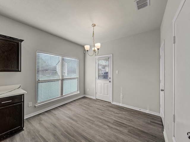 dining space with an inviting chandelier, baseboards, visible vents, and wood finished floors