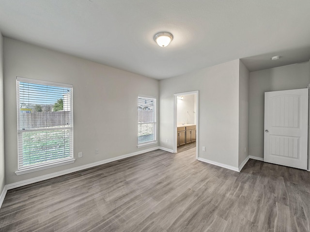 unfurnished room with baseboards, a wealth of natural light, and wood finished floors