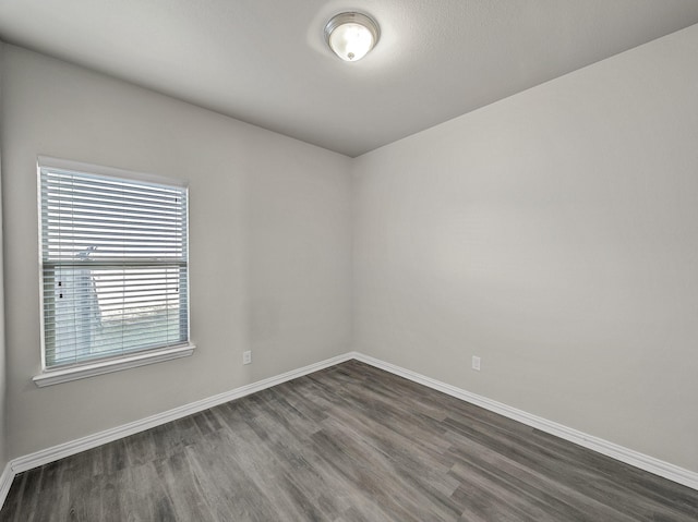 unfurnished room featuring dark wood-style flooring and baseboards