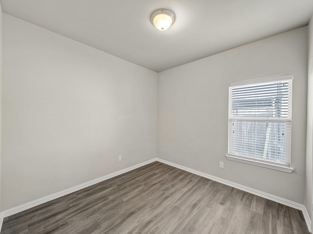 spare room featuring baseboards and wood finished floors