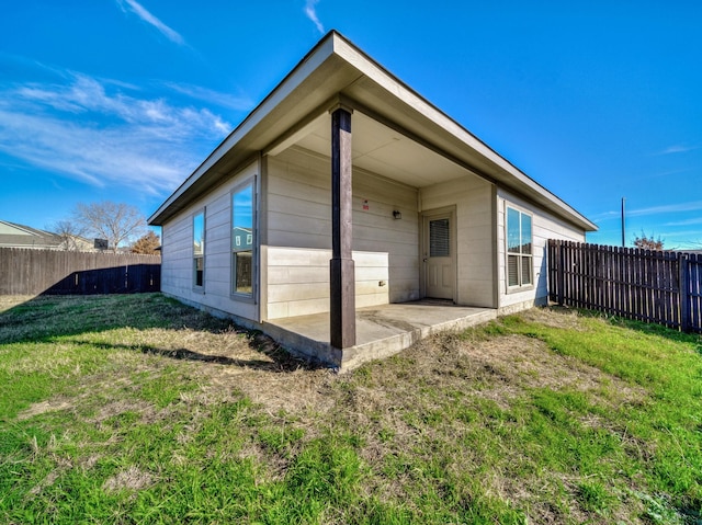 rear view of property featuring a fenced backyard, a lawn, and a patio