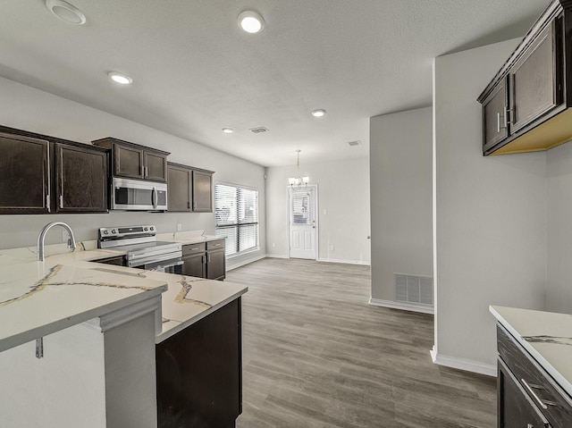 kitchen featuring dark brown cabinets, appliances with stainless steel finishes, visible vents, and light wood-style floors