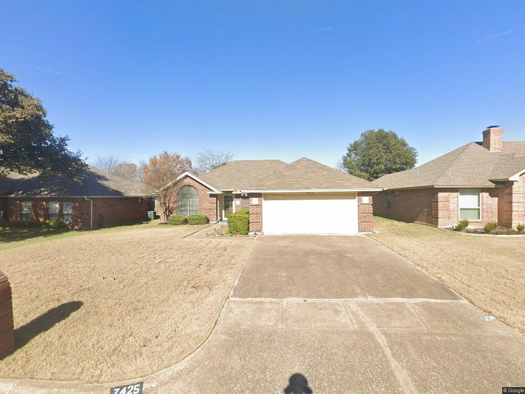 single story home featuring a garage, driveway, brick siding, and a front lawn