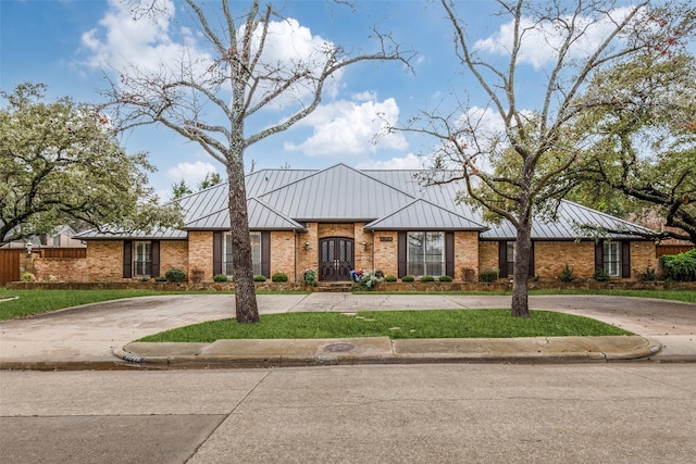 view of front of home featuring brick siding, a standing seam roof, and curved driveway