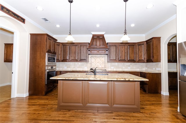 kitchen featuring arched walkways, a kitchen island with sink, dark wood-type flooring, visible vents, and appliances with stainless steel finishes