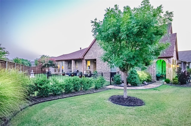 view of front of home with a front lawn, fence, and brick siding