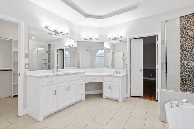 bathroom with vanity, baseboards, a shower stall, a bath, and a raised ceiling