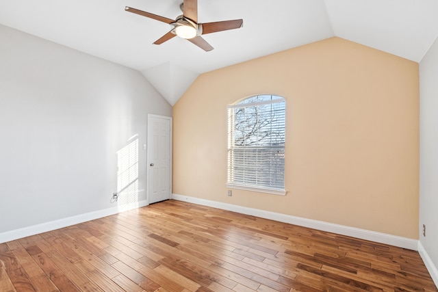 spare room featuring a ceiling fan, light wood-type flooring, vaulted ceiling, and baseboards