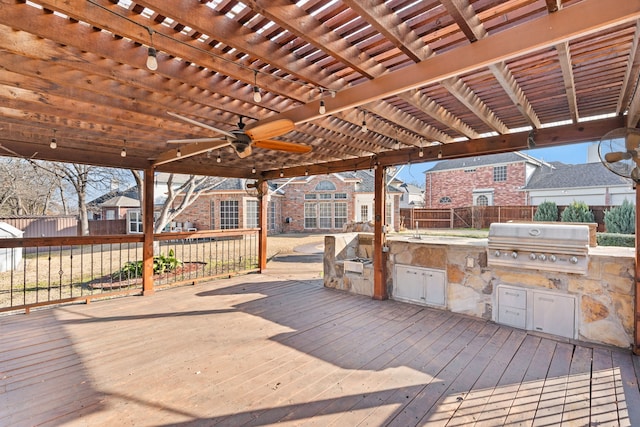 wooden terrace with exterior kitchen, a grill, fence, and a pergola