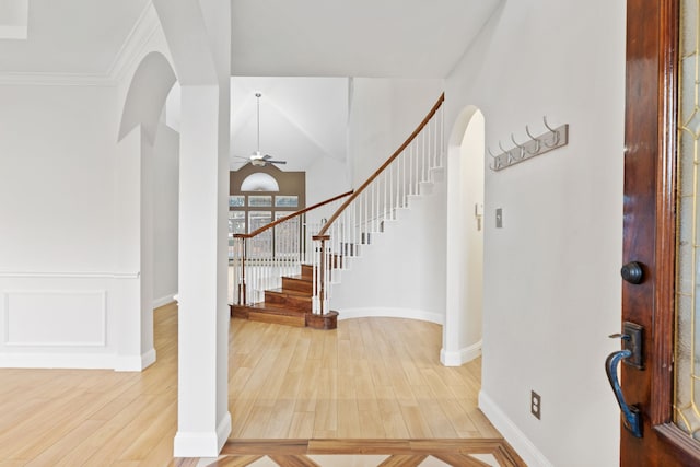 entrance foyer featuring a ceiling fan, arched walkways, stairway, and wood finished floors