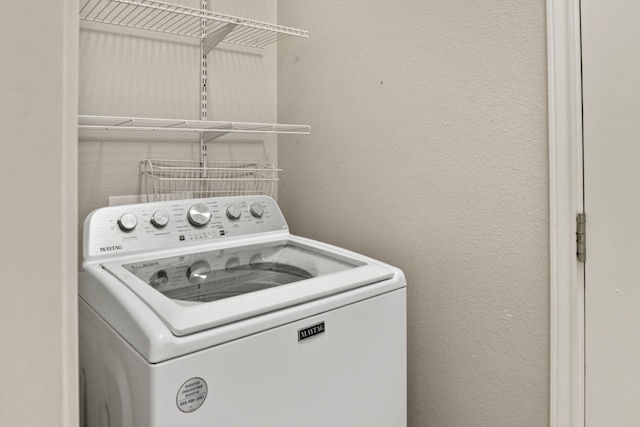 clothes washing area with a textured wall, laundry area, and washer / clothes dryer