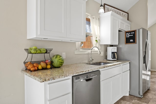 kitchen featuring appliances with stainless steel finishes, a sink, light stone countertops, and white cabinets