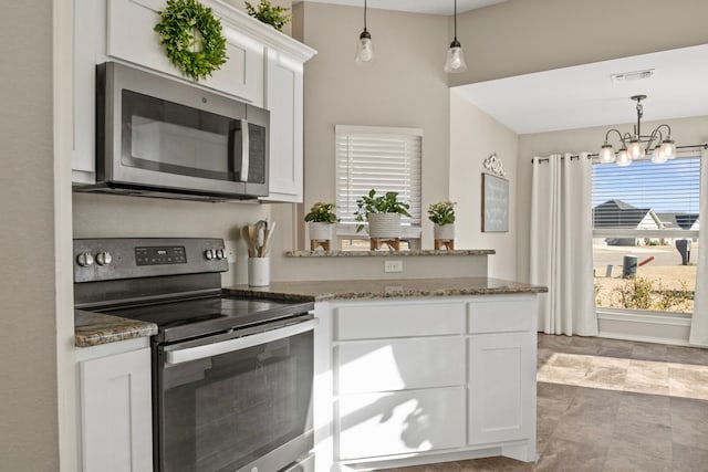 kitchen featuring dark stone counters, stainless steel appliances, a peninsula, and white cabinets