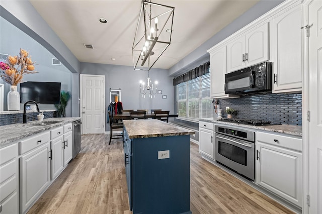 kitchen with a center island, light wood finished floors, visible vents, a sink, and black appliances