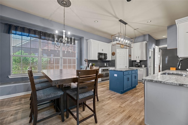 kitchen with blue cabinets, stainless steel appliances, a sink, white cabinets, and backsplash