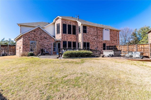 rear view of property featuring brick siding, fence, a patio, and a lawn