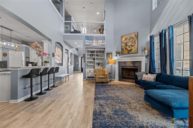 living area featuring arched walkways, wood finished floors, a wealth of natural light, and a high end fireplace