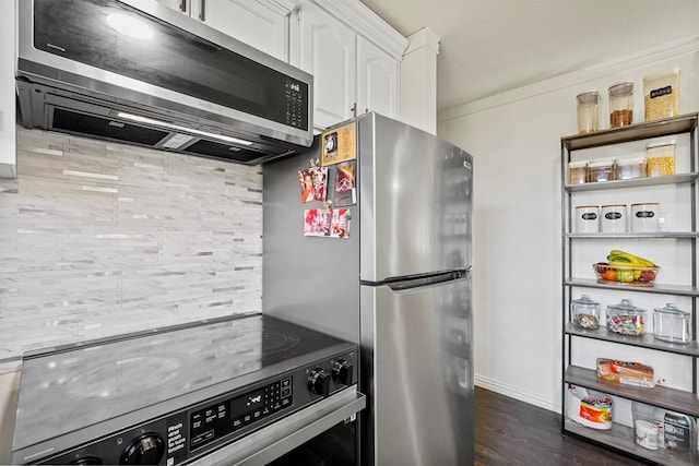 kitchen with baseboards, ornamental molding, dark wood-style flooring, stainless steel appliances, and white cabinetry