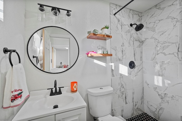 full bathroom featuring toilet, a tile shower, and vanity