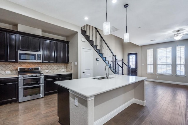 kitchen featuring appliances with stainless steel finishes, dark wood-type flooring, a sink, and tasteful backsplash