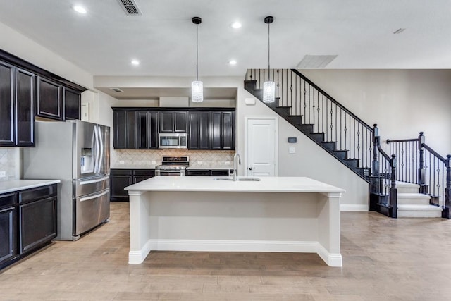 kitchen with light wood finished floors, visible vents, decorative backsplash, appliances with stainless steel finishes, and light countertops