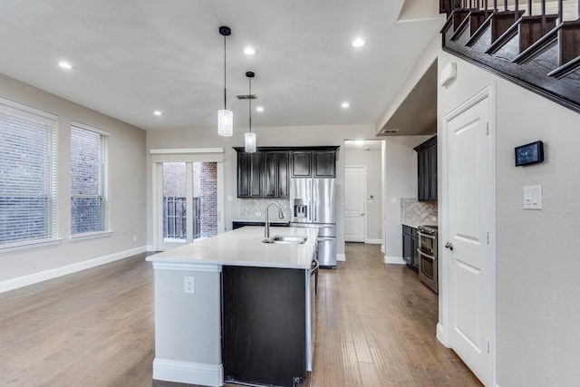 kitchen featuring stainless steel appliances, wood finished floors, a sink, visible vents, and light countertops